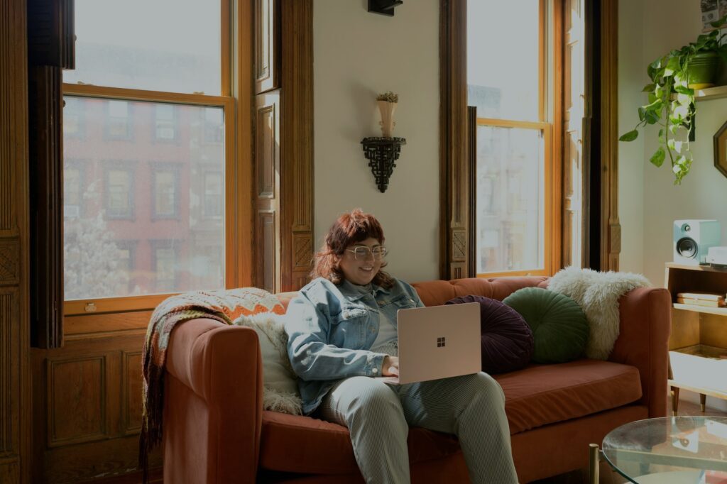 a woman sitting on a couch using a laptop computer