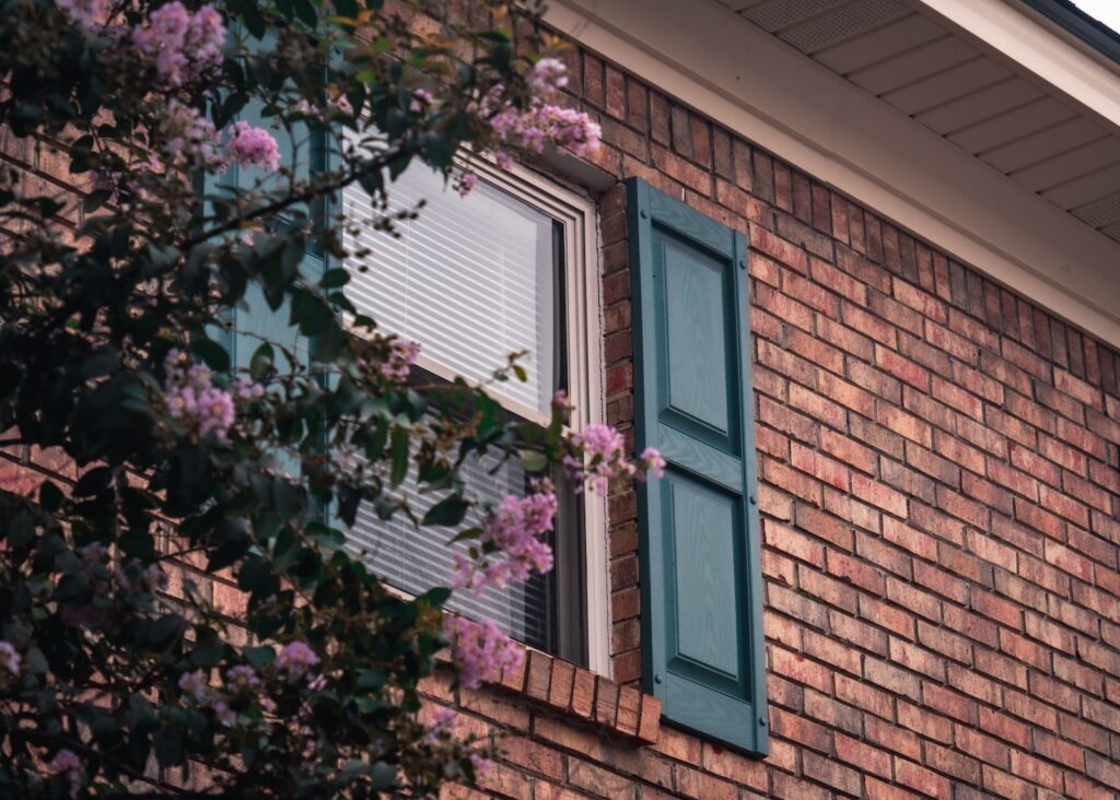 a brick building with a window and green shutters