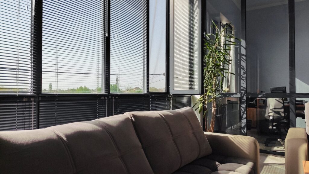 a living room filled with furniture and a window covered in blinds